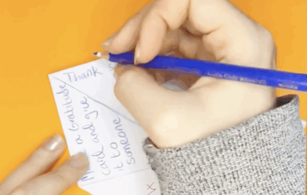 A hand holding a pencil filling in a fortune teller
