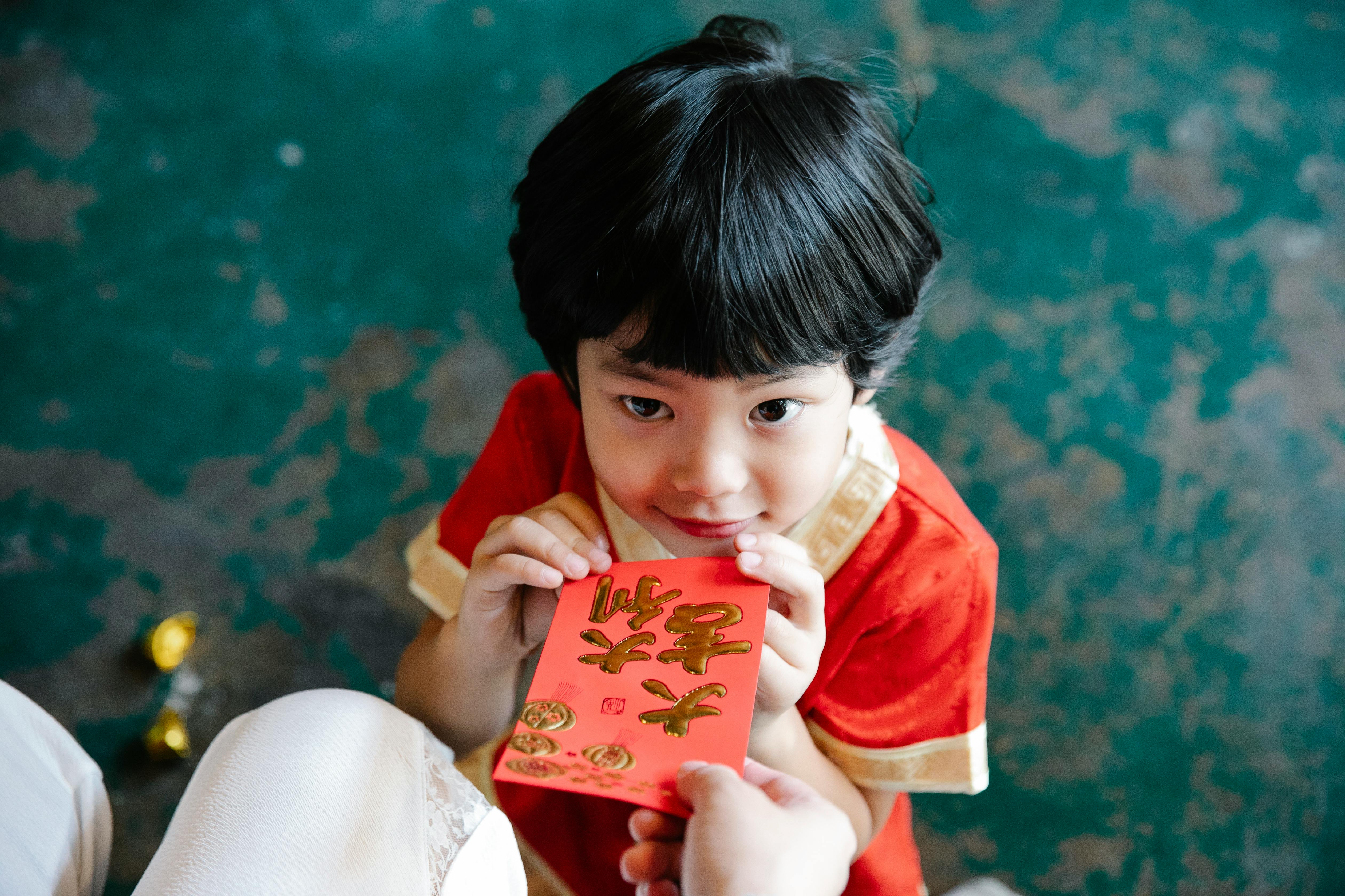 An adult giving a red envelope to a young child during Lunar New Year celebration
