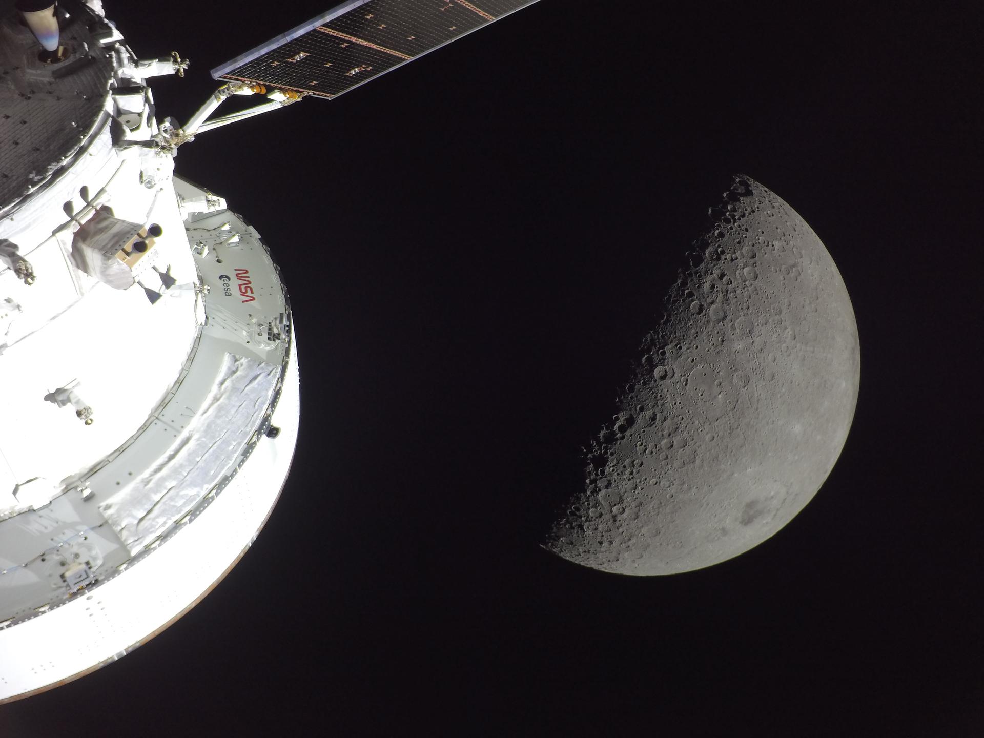 NASA's Orion spacecraft lit by sunlight in the foreground, with a first-quarter Moon visible behind it showing the Orientale basin