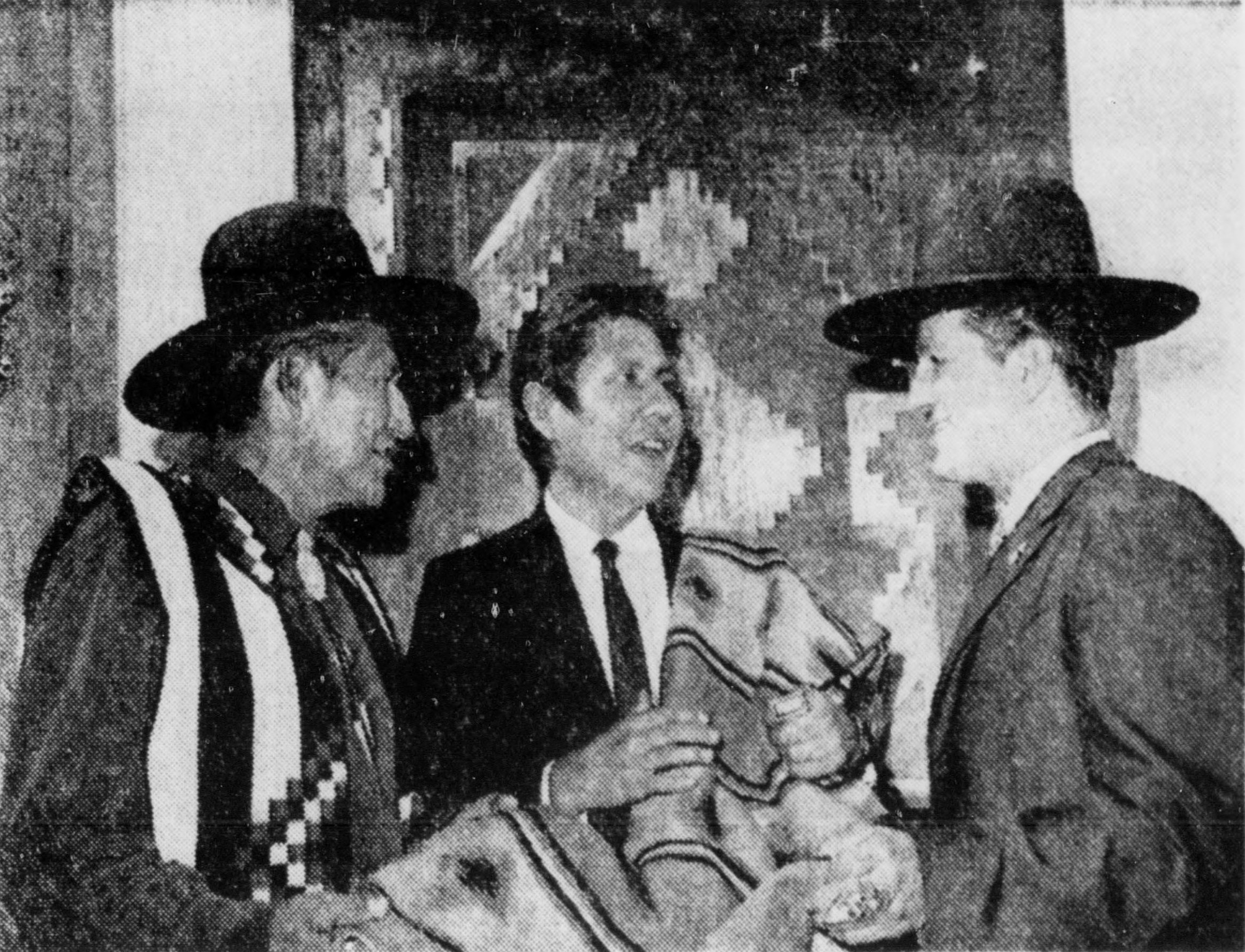 Carl Nelson Gorman and his son R. C. Gorman stand with Lloyd L. House among their paintings at an exhibition of their work in San Francisco in 1967.